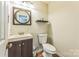 Functional half-bathroom with a single sink vanity, toilet, and a decorative mirror, providing convenience for guests at 8719 Sweet Sage Ln, Charlotte, NC 28227