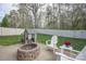 Outdoor living space with a brick fire pit, Adirondack chairs, and a charming playhouse in a fenced yard at 908 Carole Summey Dr, Dallas, NC 28034