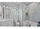 Beautiful bathroom featuring marble tile, a tub-shower, white vanity, and a large arched window at 911 Naples Dr, Davidson, NC 28036