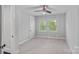 Bright bedroom with neutral carpet, a ceiling fan, and two windows with green outdoor views at 911 Naples Dr, Davidson, NC 28036