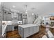 Open kitchen features gray cabinets, an island with seating, stainless steel appliances, and hardwood flooring at 911 Naples Dr, Davidson, NC 28036