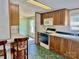 Kitchen includes wooden cabinets, microwave, stove, peninsula with barstool seating, and doorway to room with carpet at 105 Branson Dr, Olin, NC 28660