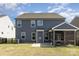 A well-maintained backyard features a gray-blue vinyl-sided home, a screened in porch, and patio area at 1077 Hearth Sw Ln, Concord, NC 28025