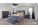 Bright bedroom with gray tufted bed, accent pillows, dresser, and a bench with an area rug at 1077 Hearth Sw Ln, Concord, NC 28025