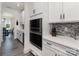 Built-in stainless steel microwave and oven sit adjacent to a butler's pantry with a gray backsplash at 1077 Hearth Sw Ln, Concord, NC 28025