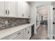 A butler's pantry with white cabinets, quartz countertops, tile backsplash and stainless steel beverage cooler at 1077 Hearth Sw Ln, Concord, NC 28025
