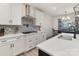 Bright kitchen has white cabinetry, stainless steel appliances, mosaic backsplash, and a dining area at 1077 Hearth Sw Ln, Concord, NC 28025