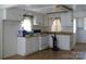 Bright kitchen with white appliances, white cabinets, and a seamless transition to an adjacent carpeted room at 1230 Roberts St, China Grove, NC 28023