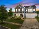 Charming two-story home with stone and siding facade, attached garage, and manicured front lawn at dusk at 12710 Es Draper Dr, Huntersville, NC 28078