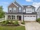 Charming two-story home featuring a stone facade, two-car garage, and well-manicured front yard at 12710 Es Draper Dr, Huntersville, NC 28078