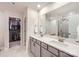 Bathroom featuring dual sinks, a large mirror, contemporary finishes, and a view into the walk-in closet at 15116 Caspian Way, Charlotte, NC 28278