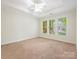 Bright bedroom featuring plush carpet, ceiling fan, and large windows offering natural light at 1910 Mezzo Ct, Matthews, NC 28105
