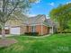 Inviting home exterior with a lush lawn, mature trees, stone accents, and a two-car garage at 1910 Mezzo Ct, Matthews, NC 28105