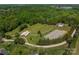 Aerial view showcasing the estate with horse stables, paddock, lush greenery, and surrounding landscape at 228 Red Dog Dr, Mooresville, NC 28115