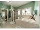 Bright bathroom with tile flooring, a shower, and a soaking tub under a large window; door leads to another room at 228 Red Dog Dr, Mooresville, NC 28115