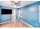 Blue bedroom featuring hardwood floors, white trim, a window, and mounted TV at 2614 Thornton Rd, Charlotte, NC 28208