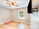 A cozy bedroom features hardwood floors, neutral walls, ceiling fan and a mounted flat screen TV at 2614 Thornton Rd, Charlotte, NC 28208