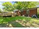Backyard view of brick home, wooden deck, lush green grass, and shaded trees creates a perfect outdoor space at 2721 Albany Ln, Charlotte, NC 28205
