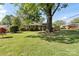 Single-story brick home on a sprawling lawn with mature trees providing ample shade at 2721 Albany Ln, Charlotte, NC 28205