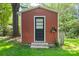 Exterior shot of a red storage shed featuring a black door, concrete steps, and metal detail on lush lawn at 2721 Albany Ln, Charlotte, NC 28205