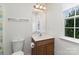 Well-lit bathroom features a toilet, window and a wooden vanity with modern fixtures at 428 Whitewater Nw Way, Concord, NC 28027