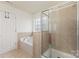 This bathroom features a bathtub, a glass shower, and neutral-toned tile at 428 Whitewater Nw Way, Concord, NC 28027