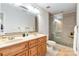 Bright bathroom featuring double sinks with granite countertops, a framed mirror, and a glass-enclosed shower with stone floor at 4925 Pageland Hwy, Monroe, NC 28112