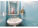 Stylish powder room with pedestal sink, decorative mirror, and neutral-toned walls at 4925 Pageland Hwy, Monroe, NC 28112