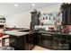 A basement wet bar featuring sleek black cabinets, granite countertops, and shelving at 4925 Pageland Hwy, Monroe, NC 28112