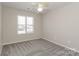 A well-lit bedroom featuring a ceiling fan and plush carpeting, illuminated by natural light from a window at 6111 Panache Dr, Matthews, NC 28104