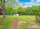 Backyard featuring an expanse of green grass, some storage buildings, and mature shade trees at 915 Gate Rd, Monroe, NC 28112
