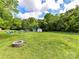 Large backyard featuring a fire pit and outbuildings, surrounded by lush greenery at 915 Gate Rd, Monroe, NC 28112