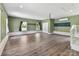 Spacious room featuring wood-look flooring, many windows, mini-split system, and a door to the stairs at 915 Gate Rd, Monroe, NC 28112
