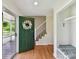 Welcoming entryway with a green front door, hardwood floors, staircase, and convenient storage bench at 915 Gate Rd, Monroe, NC 28112