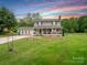 Charming two-story home with a spacious front porch, set against a colorful sunset sky and green lawn at 915 Gate Rd, Monroe, NC 28112