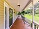 Covered front porch with wood flooring and black railing, offering a view of the green yard at 915 Gate Rd, Monroe, NC 28112