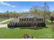 Stately brick home featuring mature landscaping and a large, manicured lawn under a blue sky at 1052 Perth Rd, Troutman, NC 28166