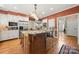 Kitchen island with seating, cooktop, stainless steel refrigerator and microwave in white cabinets at 10609 Oak Pond Cir, Charlotte, NC 28277