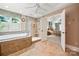 Bright bathroom with a soaking tub, tiled walk-in shower, and bedroom access at 10609 Oak Pond Cir, Charlotte, NC 28277