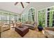 Sunroom with large windows showcasing wooded backyard, vaulted ceiling, and comfortable seating at 10609 Oak Pond Cir, Charlotte, NC 28277