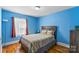 Bright bedroom featuring wood floors, blue walls, a wooden headboard and window with natural light at 1068 14Th Nw Ave, Hickory, NC 28601
