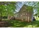 A brick home is showcased in this backyard shot, along with a back deck and lush green lawn at 1317 Waynewood Dr, Waxhaw, NC 28173
