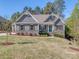 Charming home featuring stone accents, a well-manicured lawn, a teal front door and gabled roof design at 143 Robinson Ridge Dr, Mooresville, NC 28117