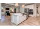 Spacious kitchen island featuring stainless steel sink, dishwasher, white cabinets, and seating with living room behind at 143 Robinson Ridge Dr, Mooresville, NC 28117