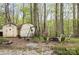 Backyard retreat featuring sheds, a fire pit, and seating area surrounded by trees at 147 Spring Shore Rd, Statesville, NC 28677