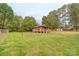Exterior of a rustic wooden shed with a quaint front porch nestled in a grassy, partially fenced yard at 212 Pine St, Rockwell, NC 28138
