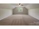 Spacious bonus room with neutral carpeting, large window, and vaulted ceiling provides versatility at 2163 Woodstream Rd, Harrisburg, NC 28075