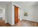 This bedroom features light hardwood floors, a sliding barn door, and a view to the outdoors at 224 Adrian St, Mount Holly, NC 28120