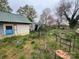 Exterior backyard view with overgrown grass and damaged furniture on a cloudy day, requiring extensive maintenance at 2702 W Stage Coach Trl, Shelby, NC 28150