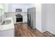 Modern kitchen with white cabinetry, stainless steel appliances, subway tile backsplash, and wood grain flooring at 409 N Apple St, Gastonia, NC 28054